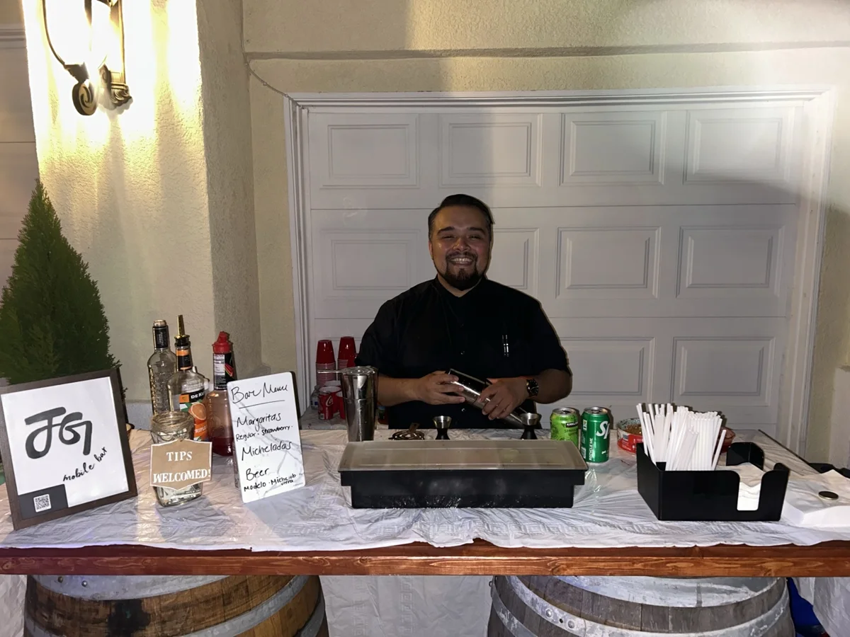 Johnny smiling behind the bar with a cocktail shaker at his first private event